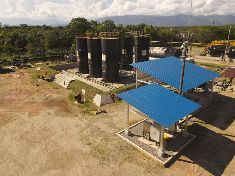 Vista aérea de tanques de almacenamiento y un cuarto eléctrico con cubierta azul sobre placa de concreto